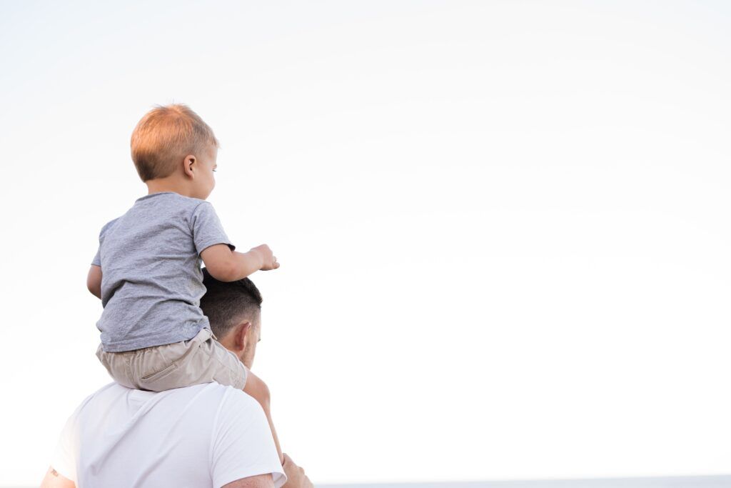 Baby on their fathers shoulders. they are so happy because they have a Trust and a Will