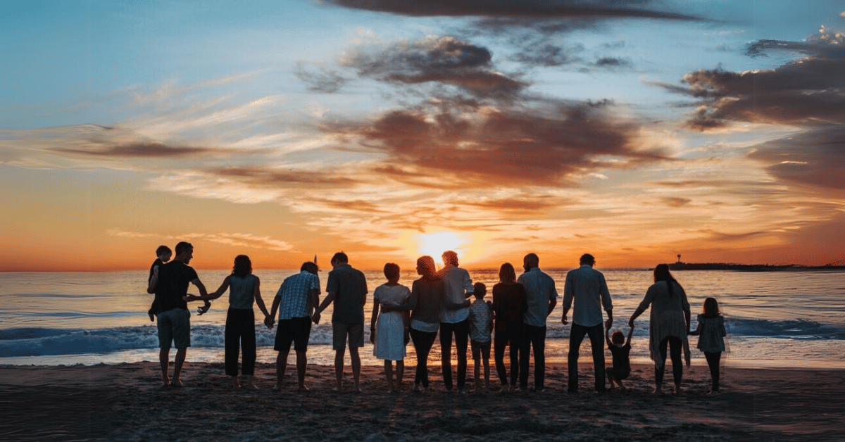 Large family gathered to watch the summer sunset on the beach, at peace because they completed their estate planning vacation checklist.